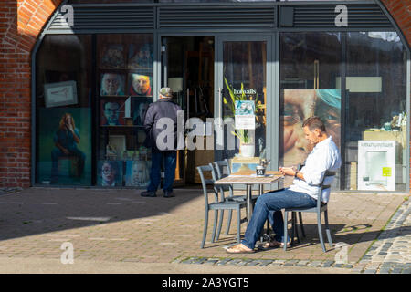 A man sitting at a table outside an art gallery Stock Photo