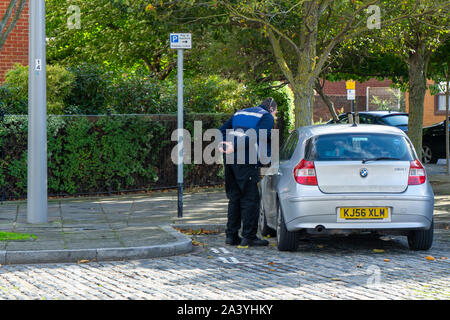 A traffic warden issuing a parking ticket on a parked car Stock Photo