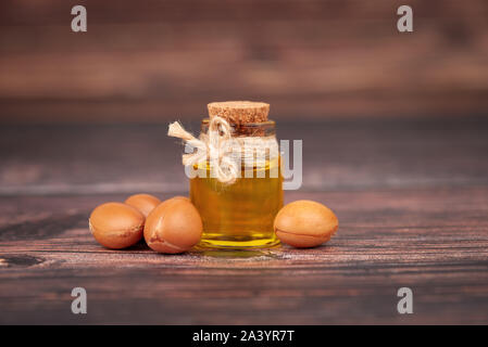 Argan oil, on wooden background. Argan nuts and seeds, for cosmetic and beauty products. Natural argan fruit from Morocco. Stock Photo