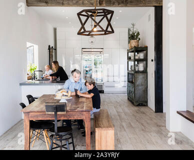 Father and son using digital tablet at dining table Stock Photo