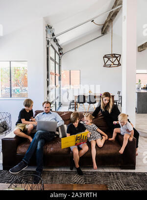 Family with book and laptop on sofa Stock Photo