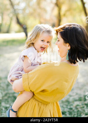 Mother holding her daughter in park Stock Photo