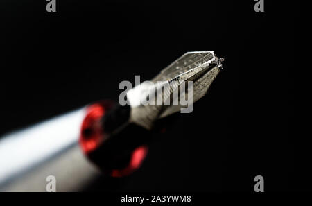 Closeup shot of Phillips Head Screwdriver Tip with Red Accent Isolated on Black Background Stock Photo