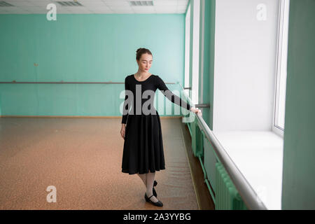 Ballet dancer wearing black dress at barre Stock Photo