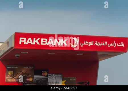 'Ras al Khaimah, RAK/ United Arab Emirates - 10/10/2019: RAK Bank red logo atm sign in evening on a main road in the northern Emriates' Stock Photo