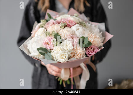 Small Beautiful bouquet of mixed flowers in woman hand. Floral shop concept. Flowers delivery. White peonies Stock Photo