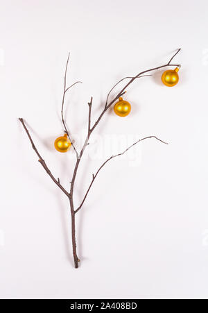 Holiday creative christmas tree concept. New Year postcard or invitation. Branch decorated with small golden balls on light background.