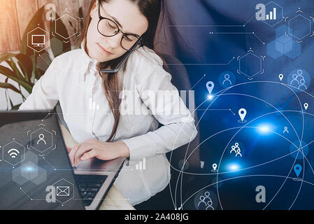 A young woman in eyeglasses using laptop with modern technology and digital layer effect as business strategy concept. Business networking communicati Stock Photo