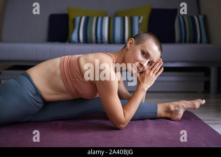 Attractive sporty woman stretching at home in split. Short-haired caucasian woman in leggins. Yoga concept Stock Photo