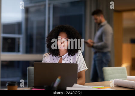 Two young creative professionals working late in a modern office Stock Photo