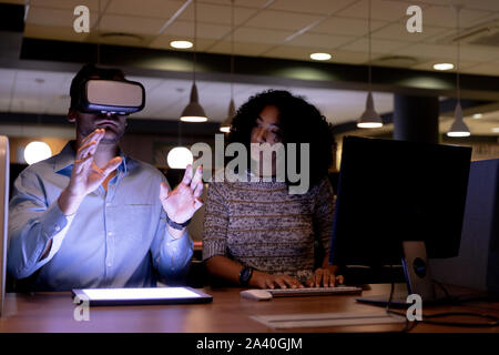 Two young creative professionals working late in a modern office using VR Stock Photo