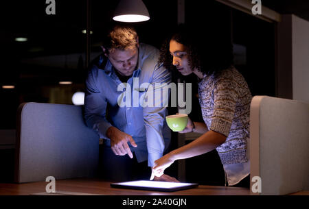 Two young creative professionals working late in a modern office Stock Photo