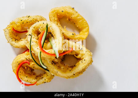 Pile of deep-fried calamari rings on the white background. Top view. With space. Stock Photo