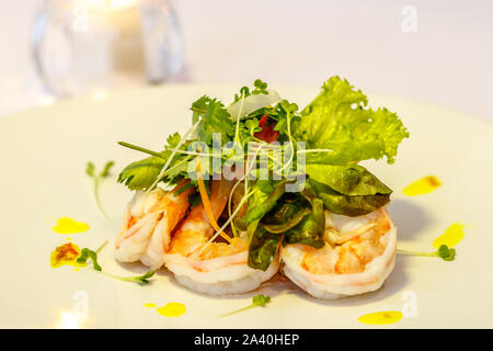White ceramic plate with Tiger prawn salad with lettuce, parsley, baby spinach and bean sprouts. Candle on the background. Top view. With space. Stock Photo