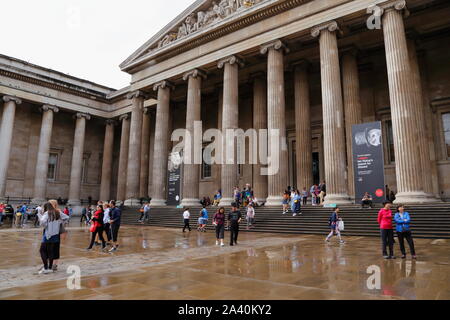 People outside in the forecourt, and infront of the main entrance to the British Museum in Bloomsbury, London, United Kingdom, on a rainy summer's day. Stock Photo