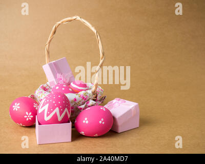 Easter eggs in a basket weave wood and gift box on the left corner on a brown background. Easter eggs multicolor with brown background. Eggs was color Stock Photo