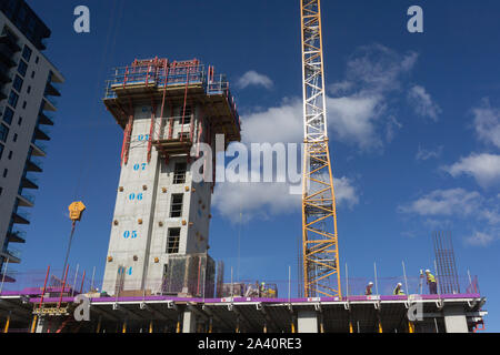 Construction workers beneath a crane and lift shaft, survey a new building complex, on 2nd October 2019, in Sutton, London, England. Stock Photo