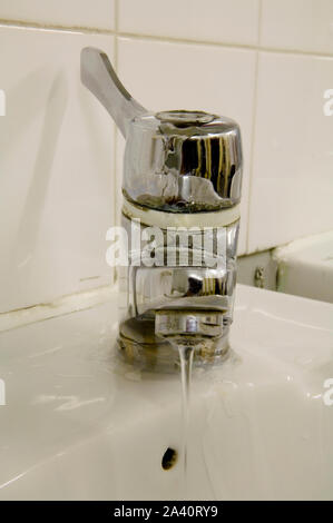 Dirty leaking mixer tap, leaking water and a waste to the environment