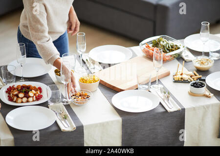 Close-up of woman putting the meal on the served table and preparing for the dinner in domestic room Stock Photo