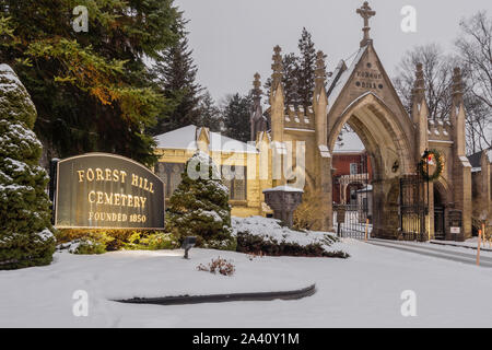 Old vintage cemetery gates architecture with snow and Christmas wreath from Forest Hills Cemetery in Utica, New York. Forest Hill Cemetery is a histor Stock Photo