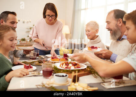 Happy big family sitting at the table and eating berry sweet pie giving by mother at home Stock Photo