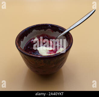 Vanilla yogurt and black cherry topping in a brown cup Stock Photo