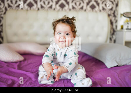 Adorable toddler sitting on bed bitting duck toy at bedroom Stock Photo ...