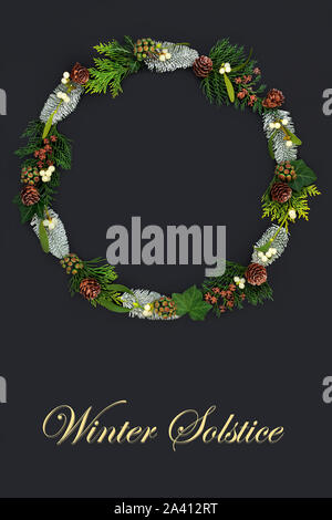 Natural winter solstice wreath with a variety of flora nd fauna on dark grey background with copy space and title. Stock Photo