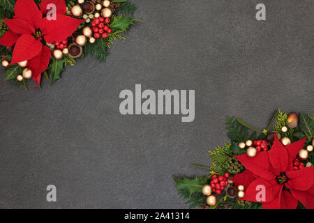 Poinsettia flower background border with winter flora and gold bauble decorations on grunge grey. Festive theme for Thanksgiving and Christmas. Stock Photo