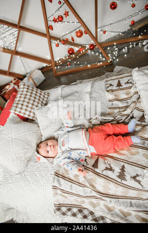 the child lies in the New Year's atmosphere. Christmas decorations for the baby. in anticipation of the festive New Year's miracle. studio shooting Stock Photo