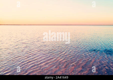 Beautiful yellow pink sunset over lake. The straight line of the horizon. Rose water in a salt lake. Stock Photo