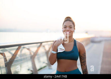 Beaming woman holding towel while walking after run Stock Photo