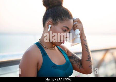 Dark-skinned young woman feeling exhausted after long run Stock Photo