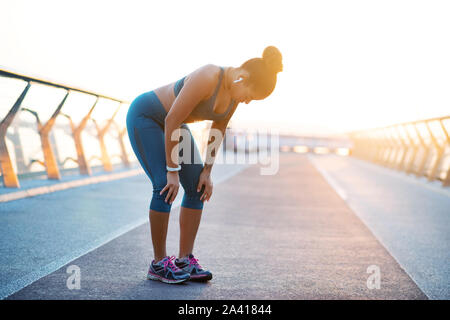 Dark-haired young woman wearing earphones breathing slow Stock Photo