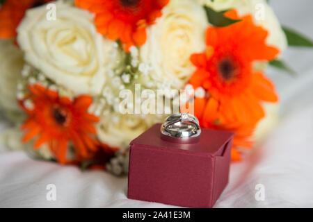 wedding bands on a ring box with the brides bouquet, waiting for the big moment, wedding rings on the wedding day Stock Photo