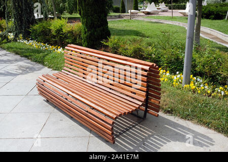 Beautiful comfortable wooden bench of brown slats with a smooth transition. Arrangement of the park comfortable places for recreation, a large wooden Stock Photo