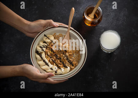 Man holding bowl with corn flakes at table Stock Photo