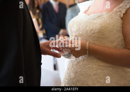 Bride and groom close up of their hands as they exchange rings on their wedding day, no faces are seen in this image, wedding day exchange of rings Stock Photo