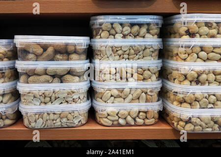 peanuts and almonds in plastic containers on the shelf. sale of shelled nuts in boxes. Delicious and healthy snack for vegetarians. Stock Photo