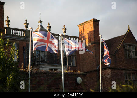 Three Union Jack flags blowing in the breeze outside a country house in England. British flag flying high in these Brexit uncertain times. Stock Photo