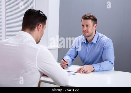 Portrait Of A Young Businessman Having Discussion With His Colleague In Office Meeting Stock Photo