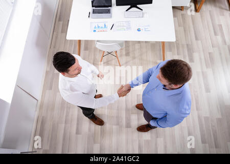 An Elevated View Of Two Businessmen Standing In The Office Shaking Hands Stock Photo