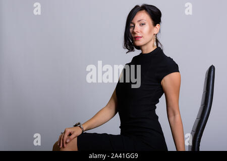 Studio shot of young beautiful businesswoman sitting on chair Stock Photo