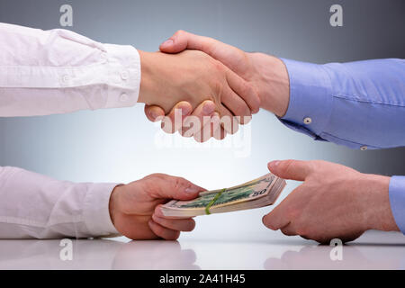 Close-up Of Businessmen Sealing The Deal With Handshake And Receiving A Bribe Money Stock Photo