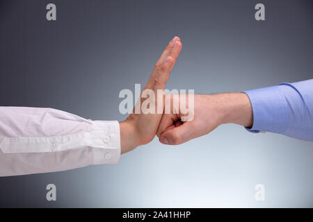 Close-up Of A Businessman Defending Himself From Punch Against Gray Background Stock Photo