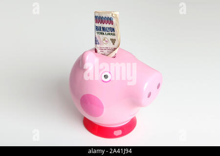 One Million Turkish Lira sticking out of a cute pink Piggy Bank made of china in shape of pigs head isolated on white background Stock Photo