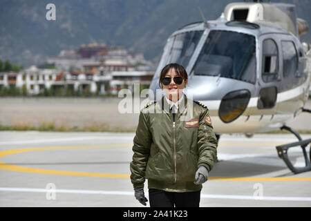 (191011) -- LHASA, Oct. 11, 2019 (Xinhua) -- Jianre Yixi walks before a helicopter in southwest China's Tibet Autonomous Region, Aug. 7, 2019. The Qinghai-Tibet Plateau was once known as a 'no-fly zone' and it was extremely difficult to fly helicopters there. Now, after professional and intensive training, the first batch of young Tibetans has flown civilian helicopters to the Mt. Qomolangma base camp. Jianre Yixi is from an impoverished herdsman family in Damxung County, Tibet. In 2016, Jianre Yixi, a student at Lhasa's No. 2 Secondary Vocational and Technical School, received a call to c Stock Photo