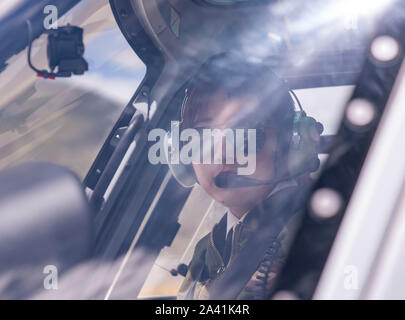 (191011) -- LHASA, Oct. 11, 2019 (Xinhua) -- Jianre Yixi prepares to fly a helicopter in southwest China's Tibet Autonomous Region, Aug. 7, 2019. The Qinghai-Tibet Plateau was once known as a 'no-fly zone' and it was extremely difficult to fly helicopters there. Now, after professional and intensive training, the first batch of young Tibetans has flown civilian helicopters to the Mt. Qomolangma base camp. Jianre Yixi is from an impoverished herdsman family in Damxung County, Tibet. In 2016, Jianre Yixi, a student at Lhasa's No. 2 Secondary Vocational and Technical School, received a call t Stock Photo