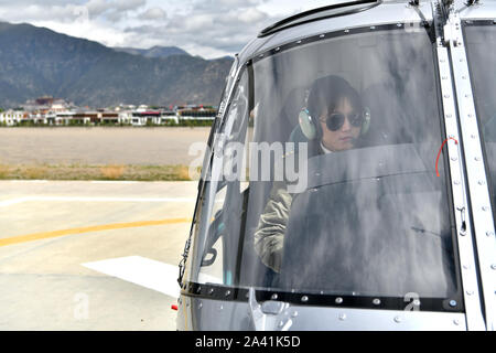 (191011) -- LHASA, Oct. 11, 2019 (Xinhua) -- Jianre Yixi prepares to fly a helicopter in southwest China's Tibet Autonomous Region, Aug. 7, 2019. The Qinghai-Tibet Plateau was once known as a 'no-fly zone' and it was extremely difficult to fly helicopters there. Now, after professional and intensive training, the first batch of young Tibetans has flown civilian helicopters to the Mt. Qomolangma base camp. Jianre Yixi is from an impoverished herdsman family in Damxung County, Tibet. In 2016, Jianre Yixi, a student at Lhasa's No. 2 Secondary Vocational and Technical School, received a call t Stock Photo