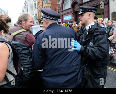 Oxford Street, London, UK. 11th October 2019. A protester is detained by police. Extinction Rebellion climate change protesters on Oxford Street. Credit: Matthew Chattle/Alamy Live News Stock Photo